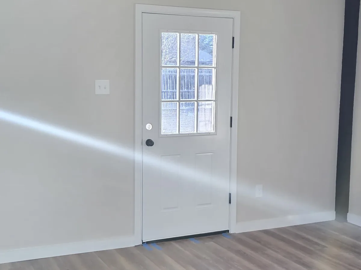Freshly painted interior wall beside a white entry door with glass panes